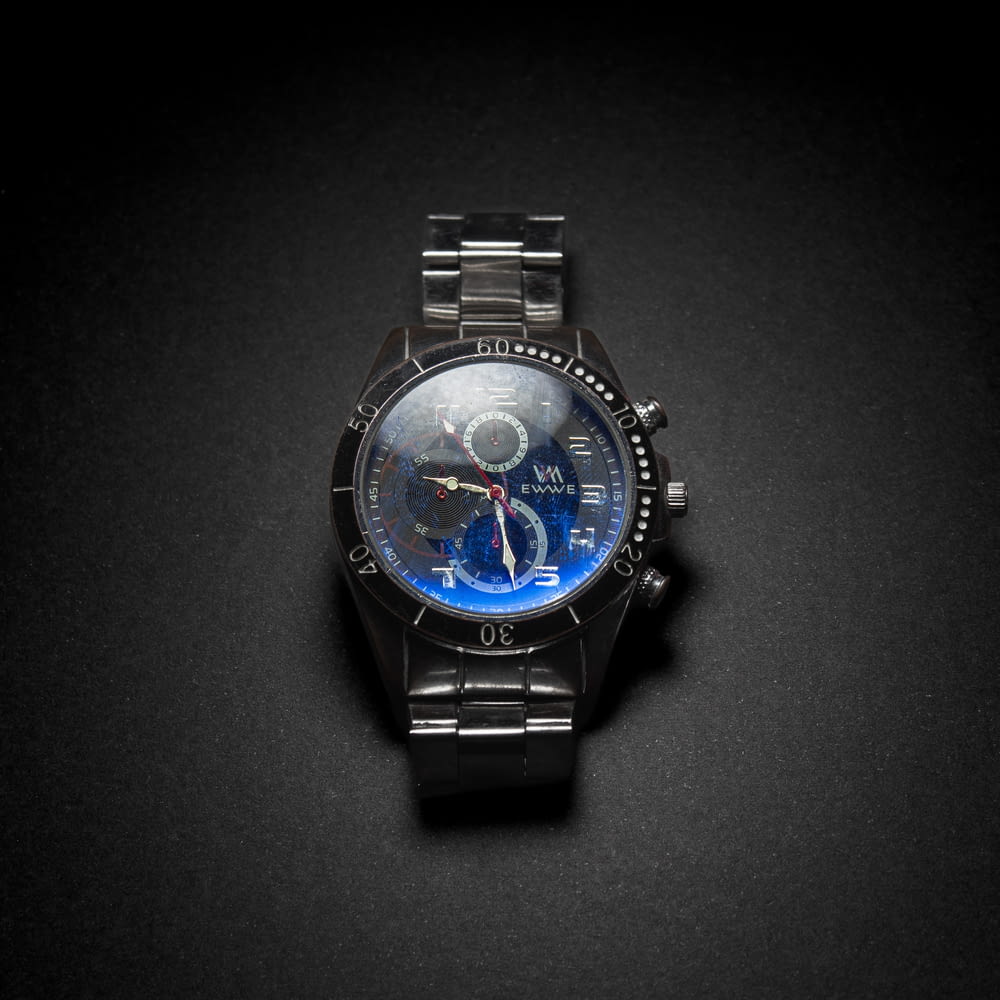 a black watch with a blue face on a black surface