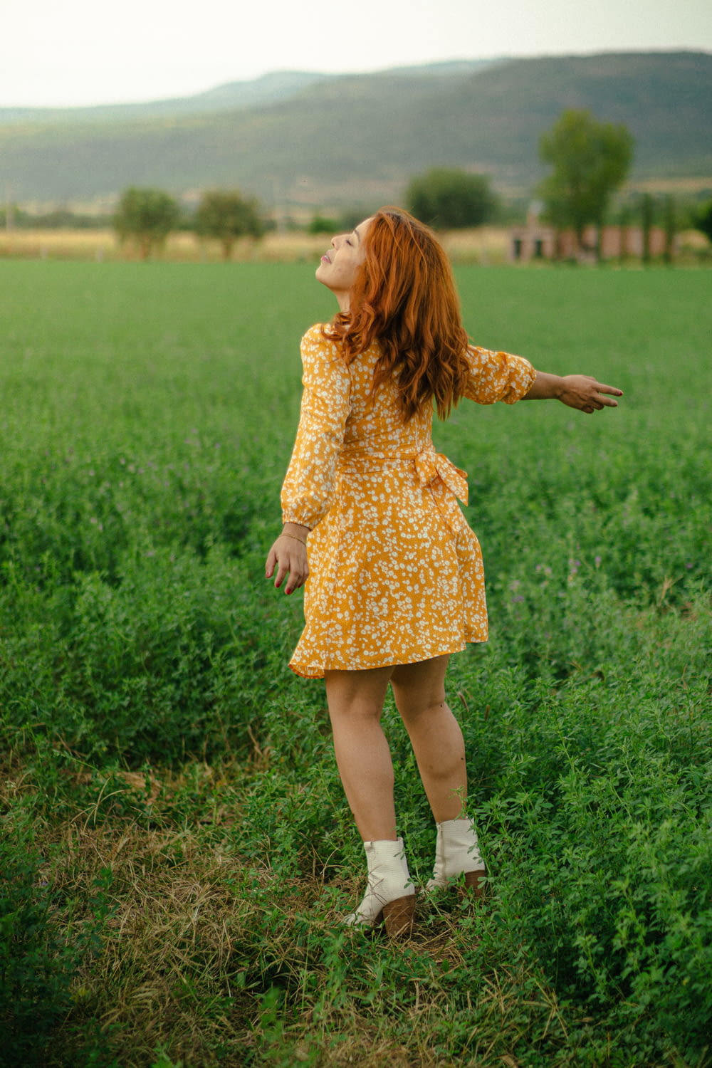 a woman in a yellow dress standing in a field