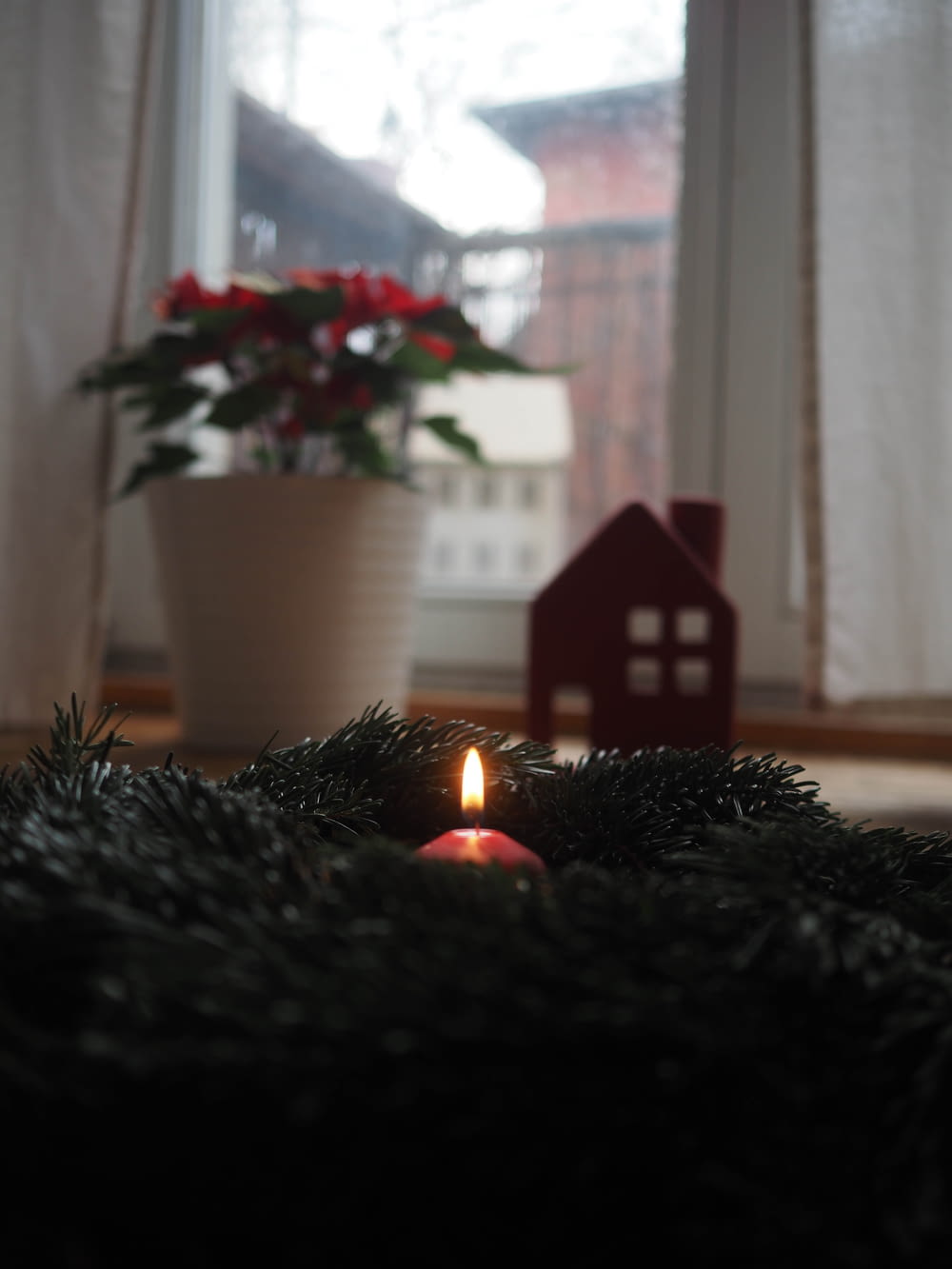 a lit candle on the floor in front of a window