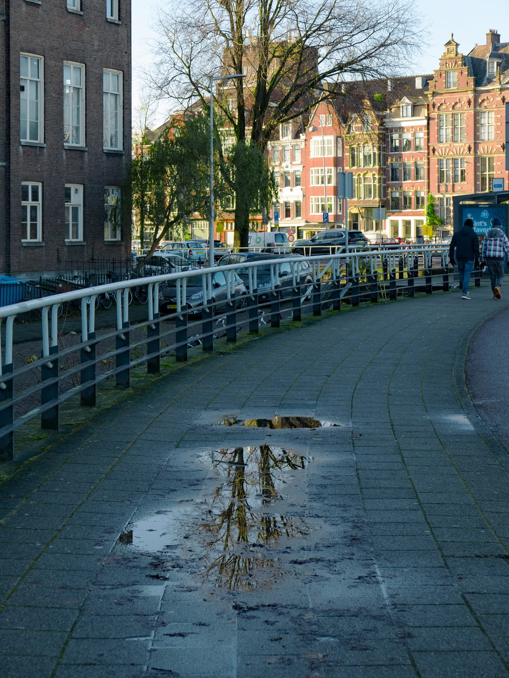 a man walking down a street next to a puddle of water