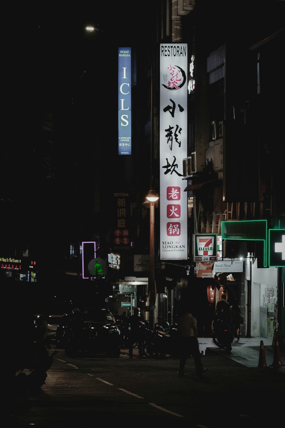 a dark city street at night with a neon sign