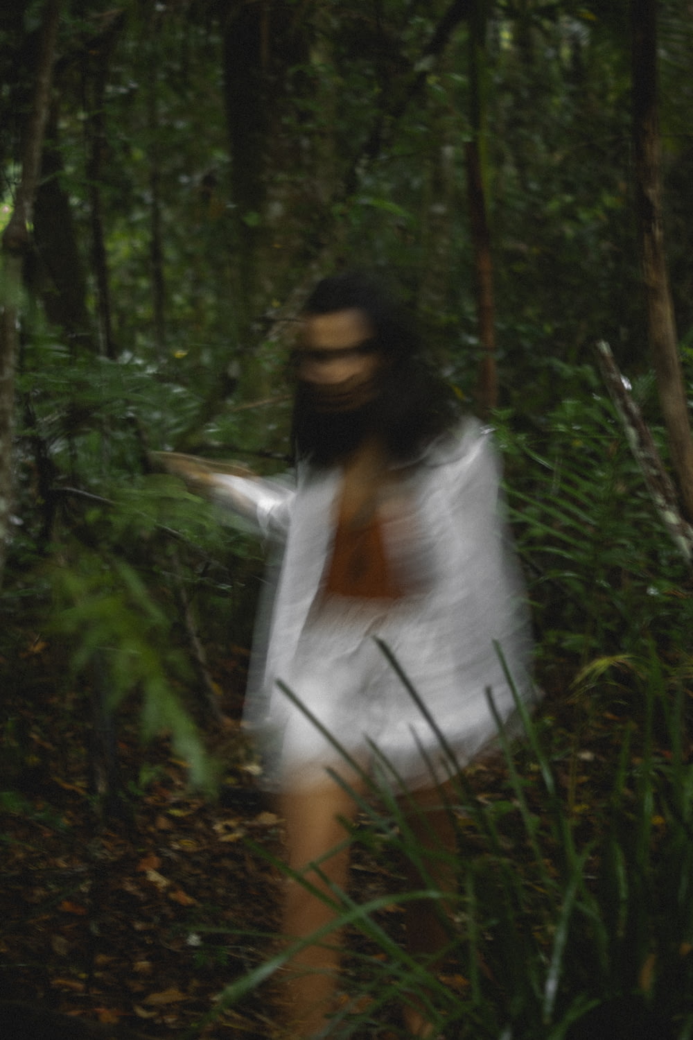 a blurry image of a woman walking through a forest