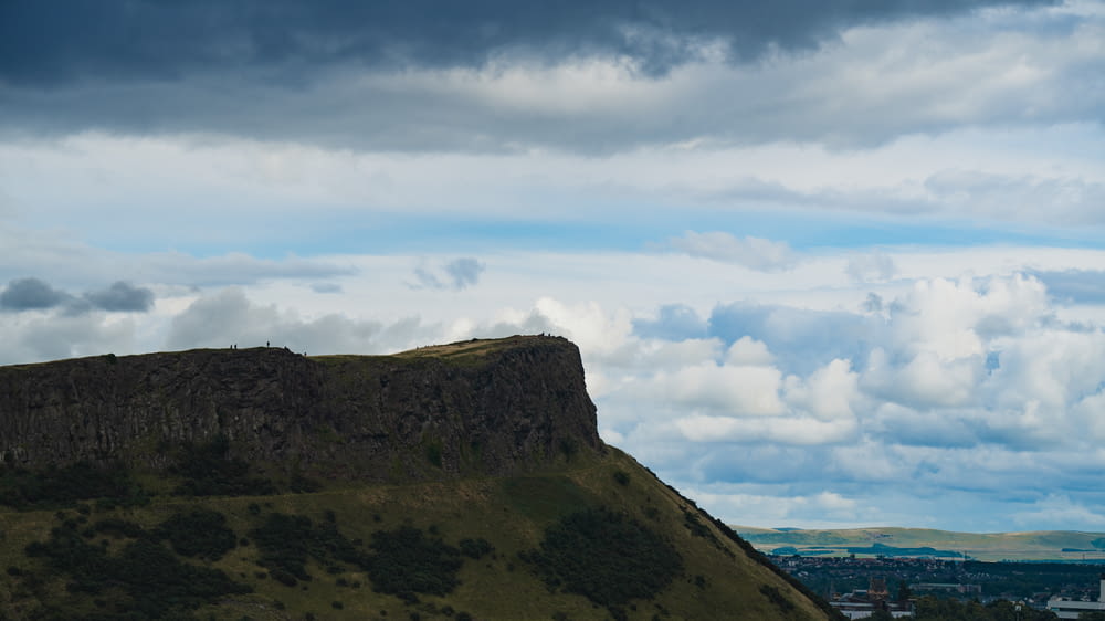 a large hill with a sky filled with clouds