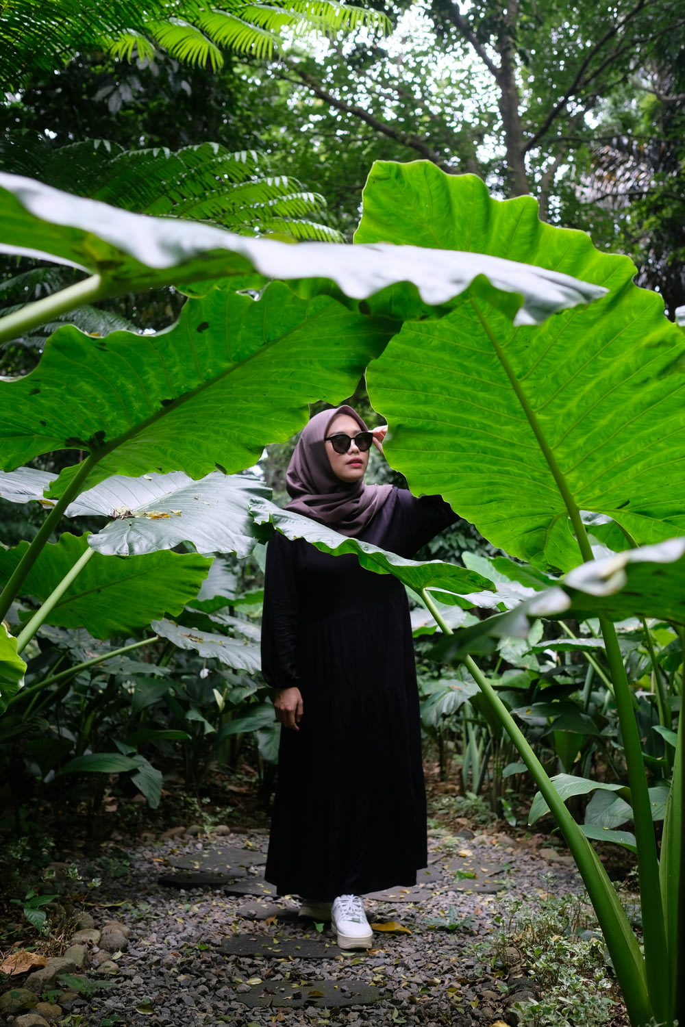 a woman wearing a hijab standing in the middle of a jungle