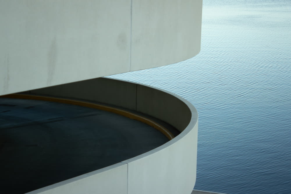 a curved concrete wall next to a body of water
