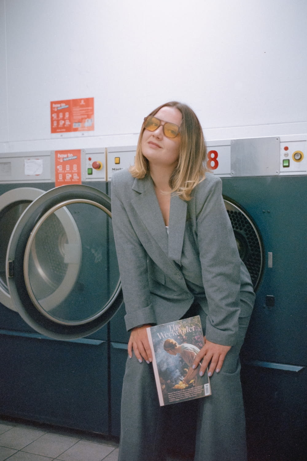 a woman standing in front of a dryer holding a book