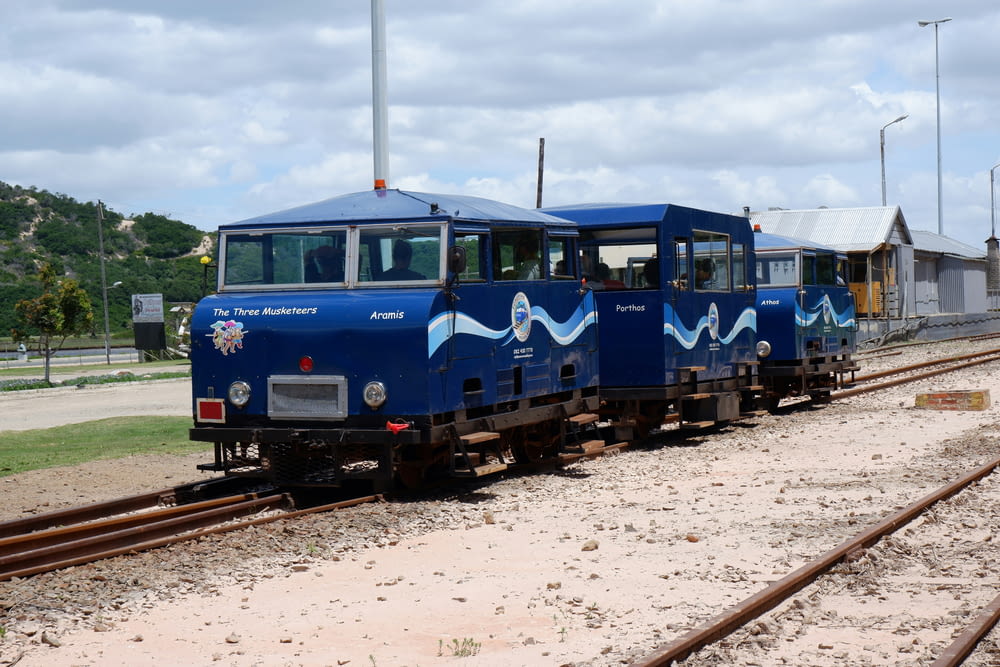 a couple of blue trains sitting on top of train tracks