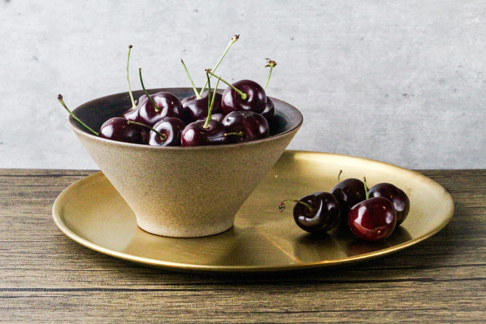 a bowl of cherries on a gold plate