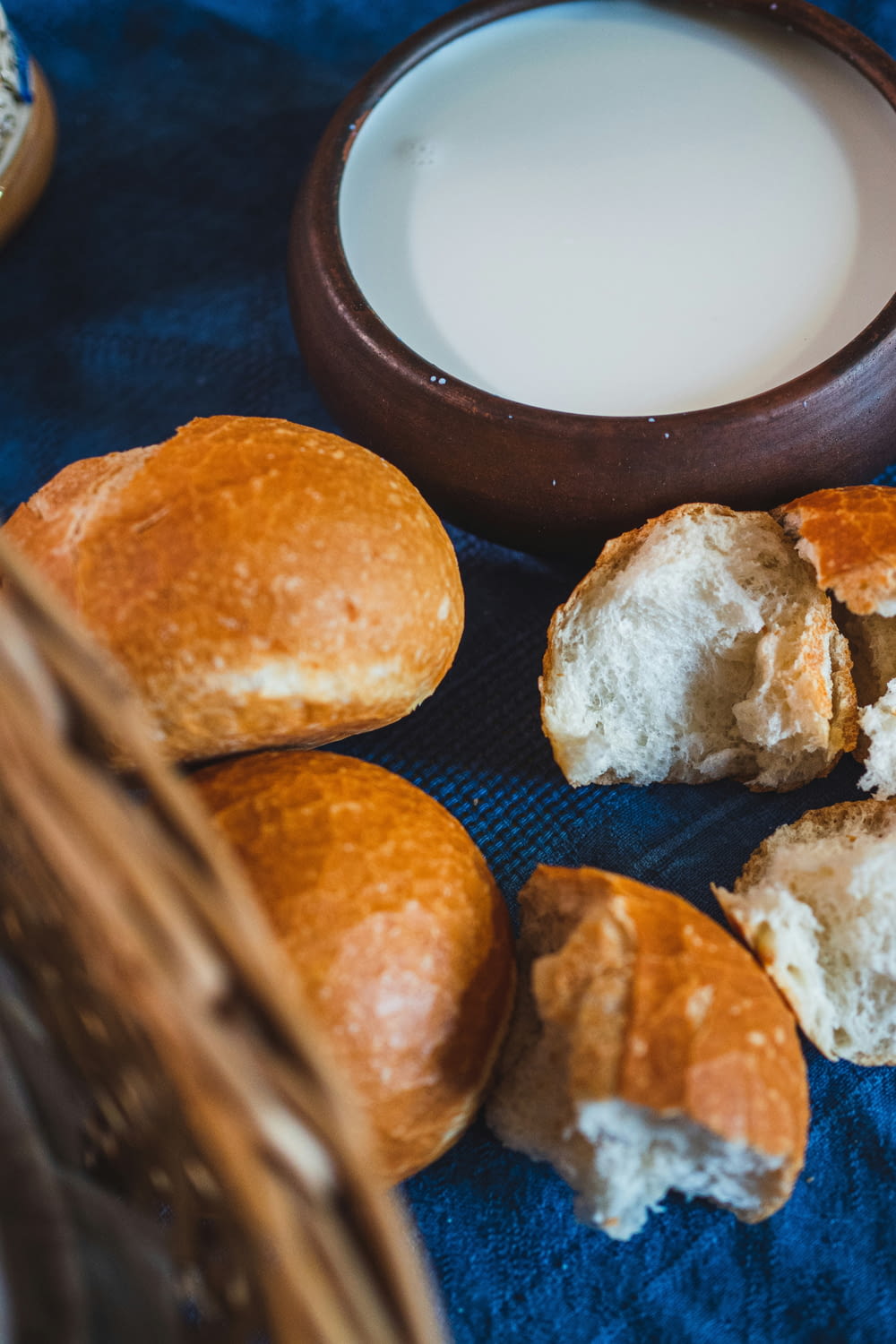 a basket of bread next to a bowl of milk