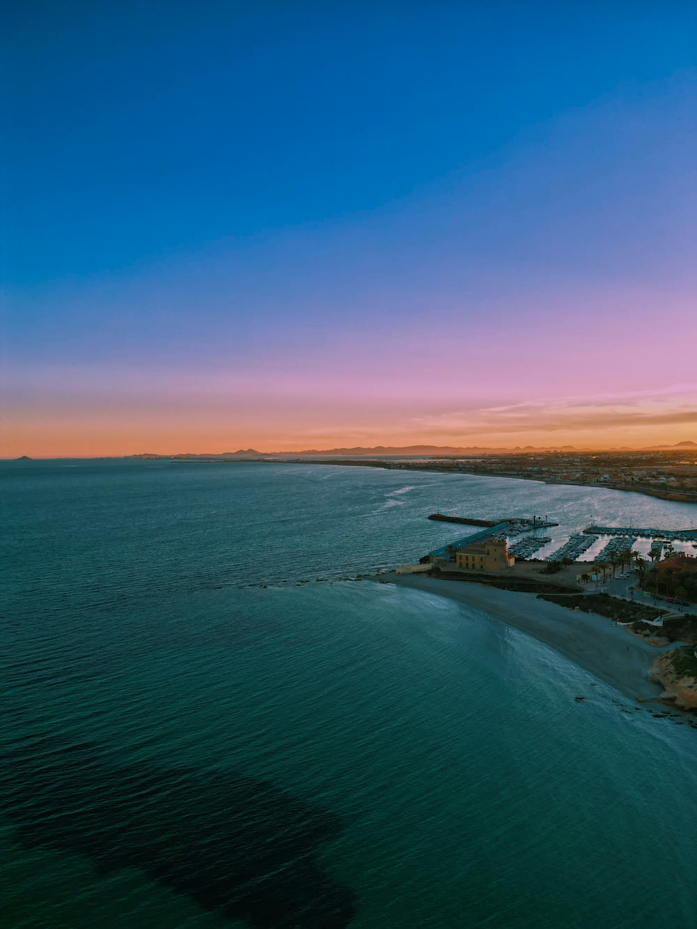 an aerial view of a beach and a city at sunset