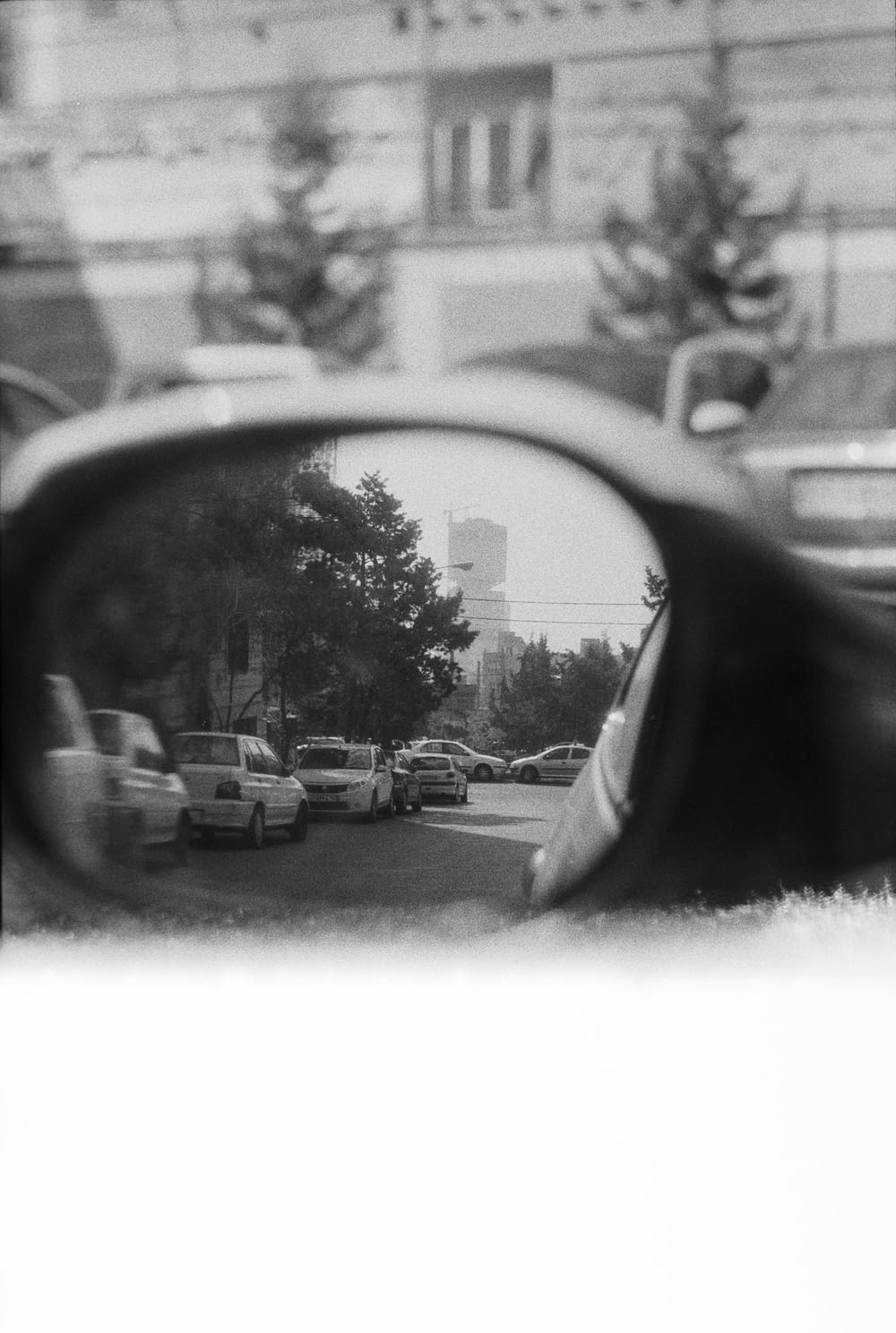 um espelho retrovisor refletindo carros em uma rua da cidade
