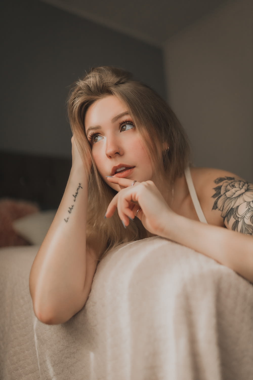 a woman sitting on a bed with a tattoo on her arm
