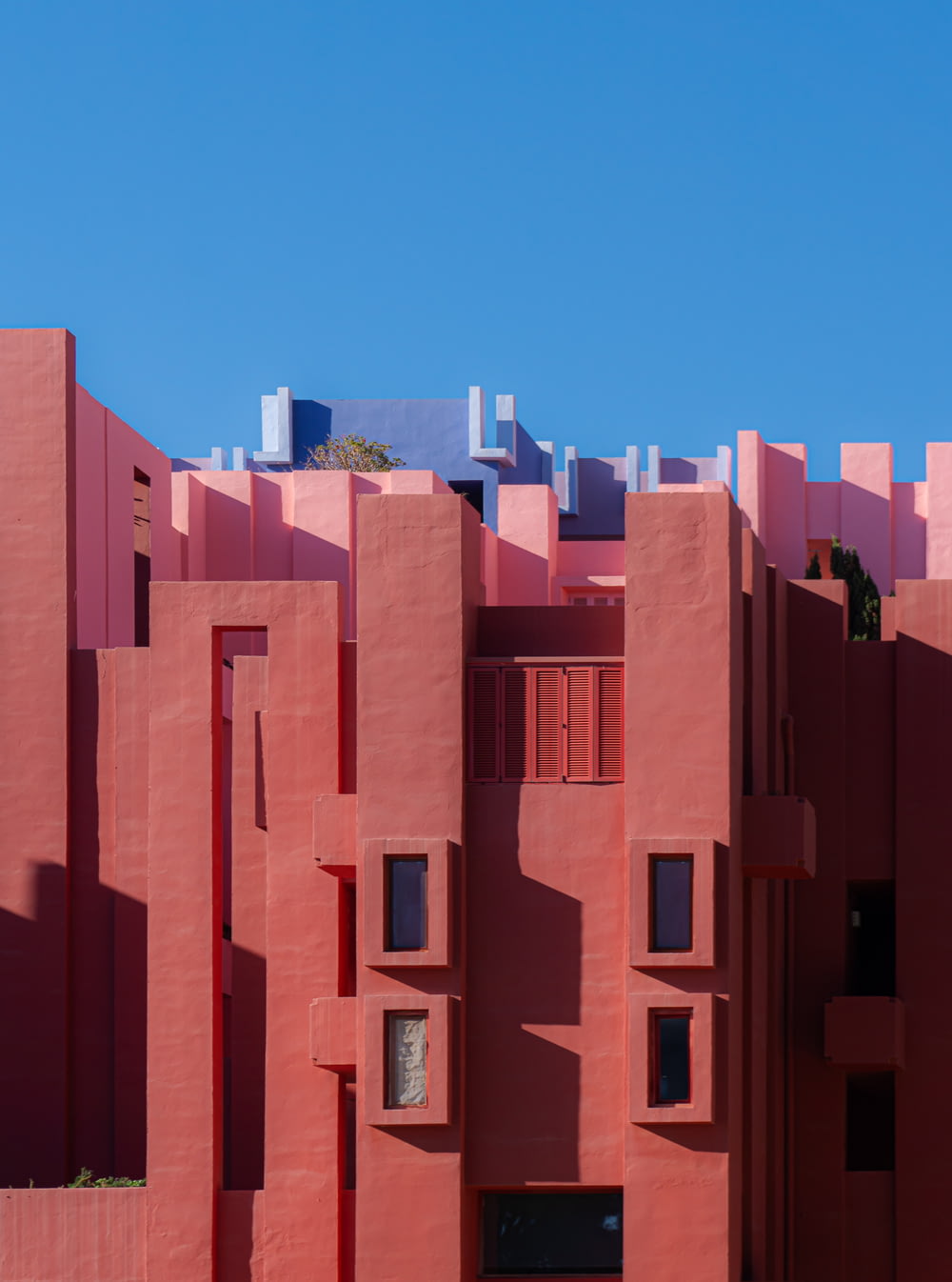 a red building with many windows and a sky background
