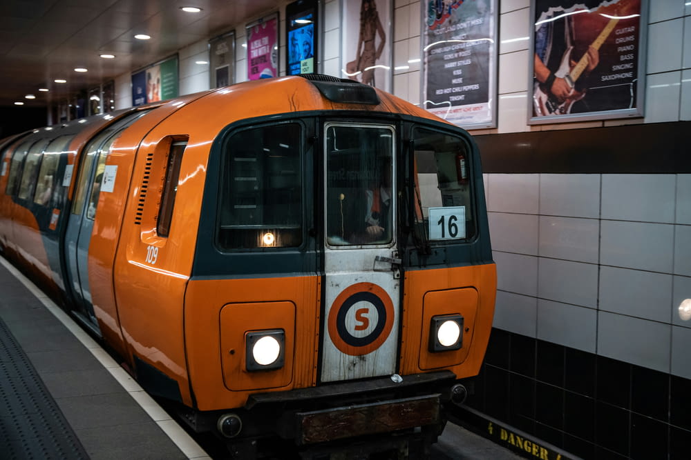 an orange train pulling into a train station