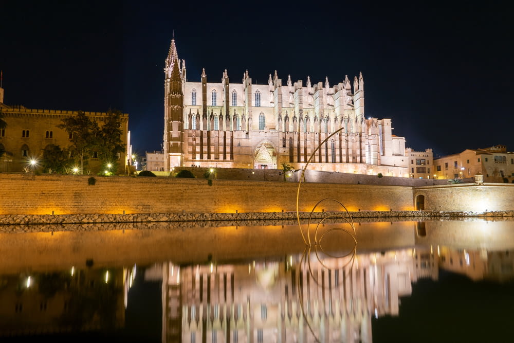 a large cathedral lit up at night next to a body of water