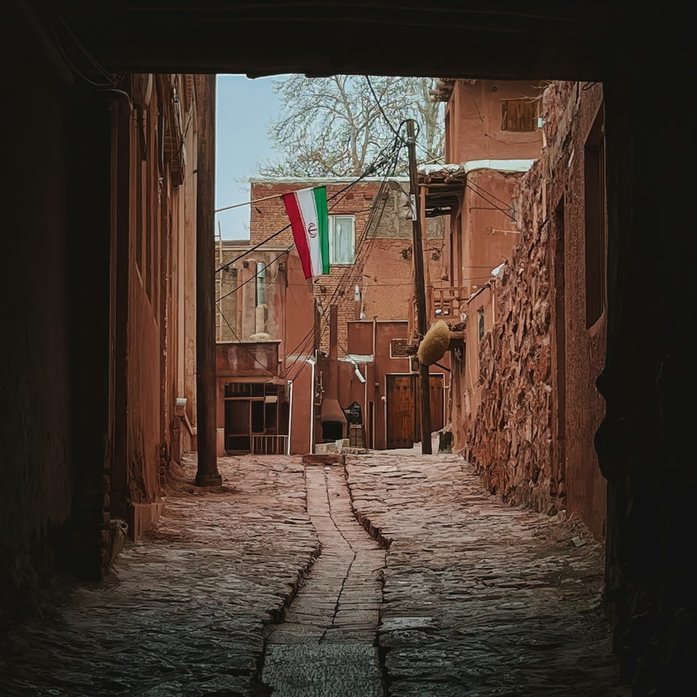 a narrow alley way with a flag on a pole