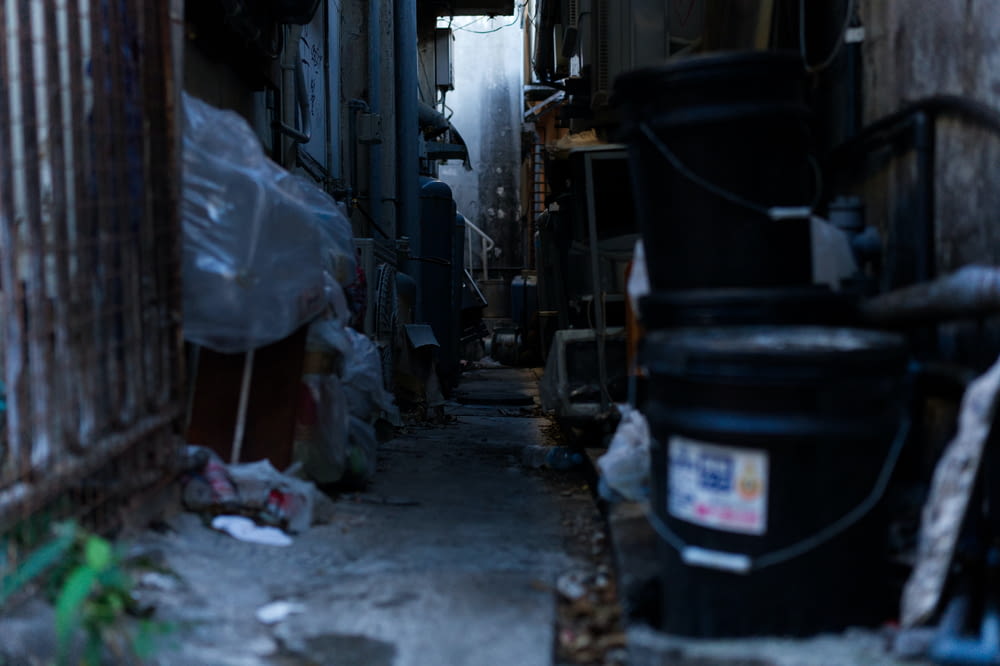a narrow alley way with trash cans and garbage cans