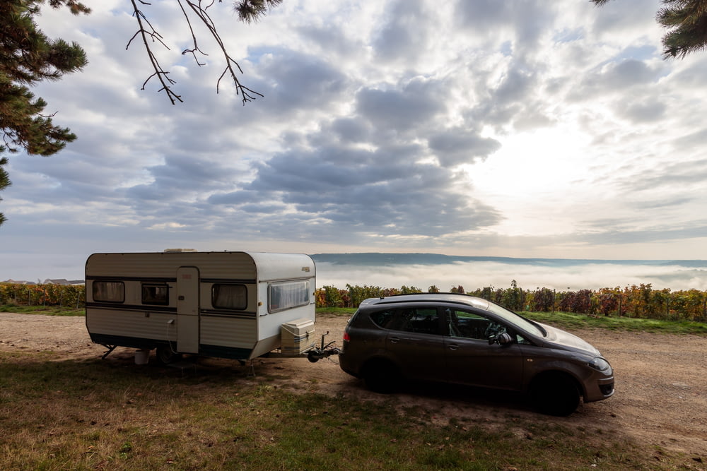 a car parked next to a camper on a dirt road