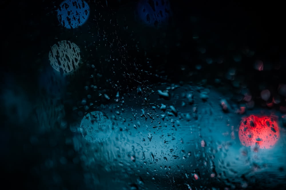 a rain covered windshield with a red stop light in the background