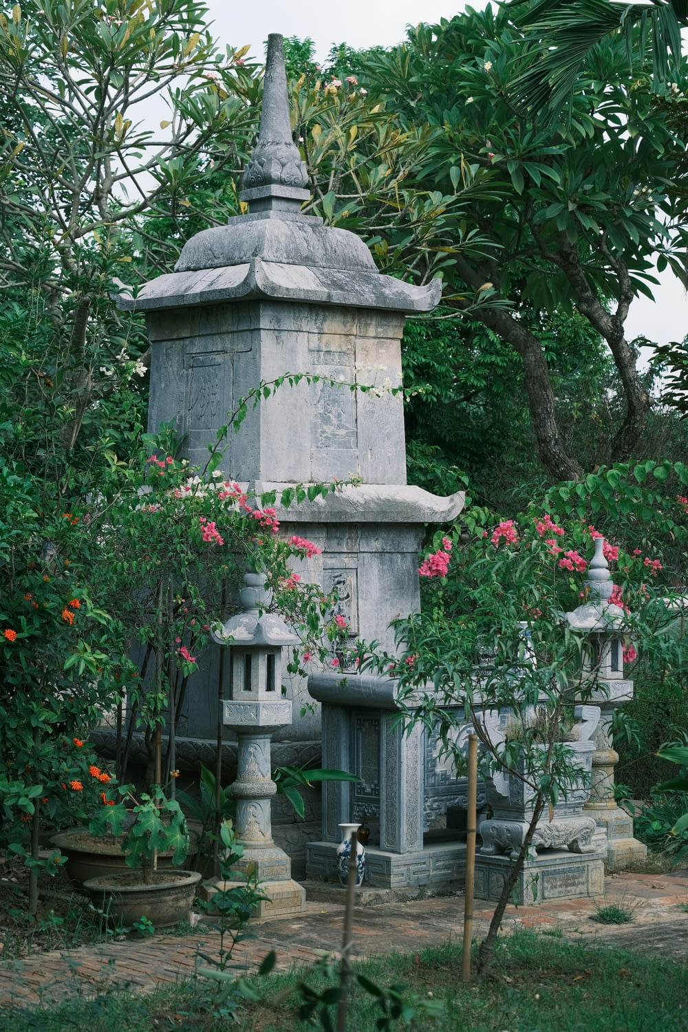 a stone monument surrounded by trees and flowers
