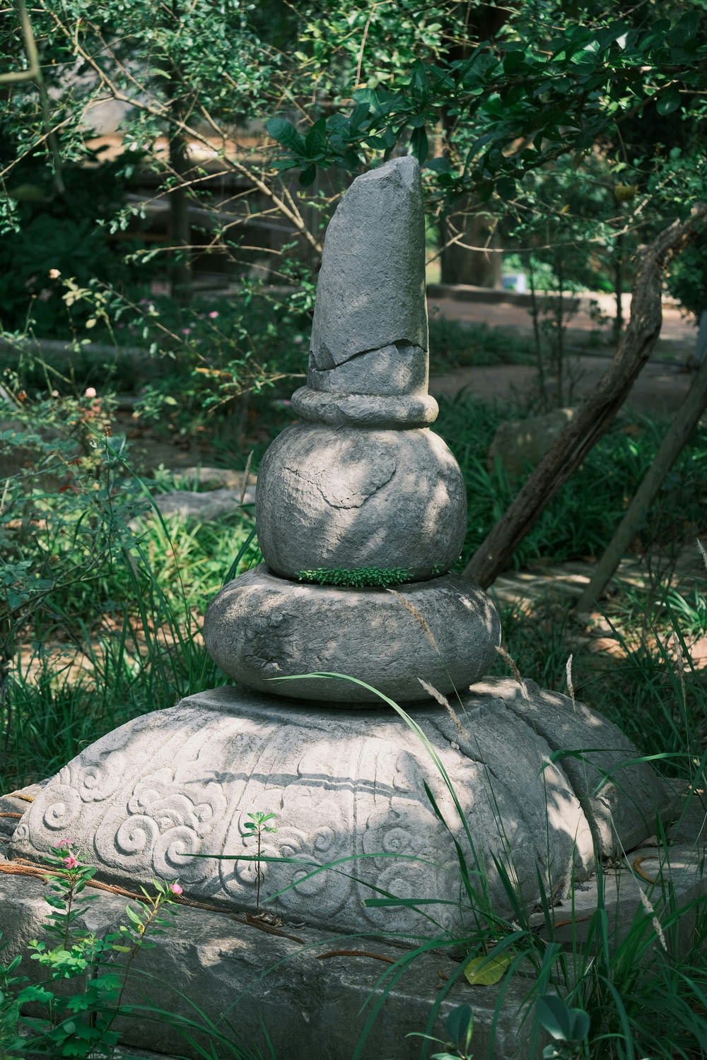 a stone statue sitting in the middle of a forest