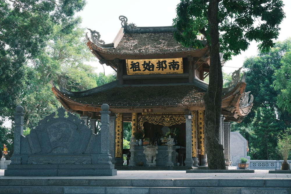a chinese shrine with a tree in the foreground