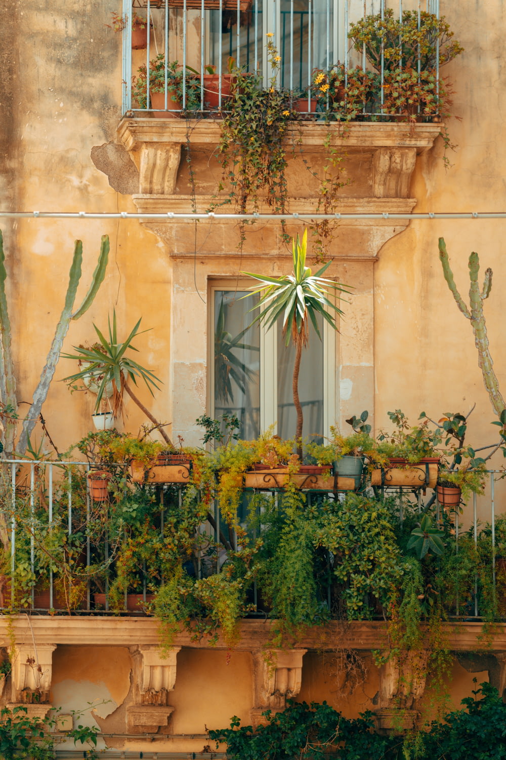 a balcony filled with potted plants next to a building