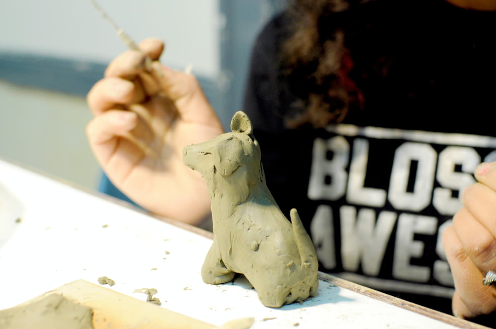 a woman is working on a clay animal