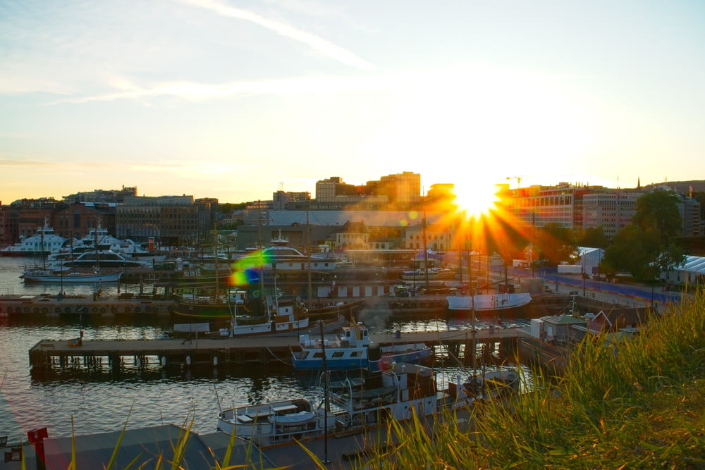 the sun is setting over a harbor with boats