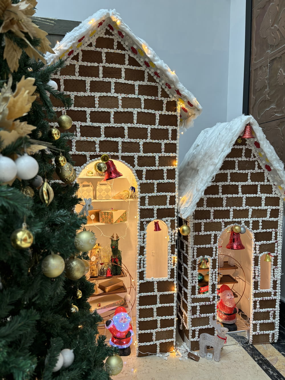 a gingerbread house with a christmas tree in front of it