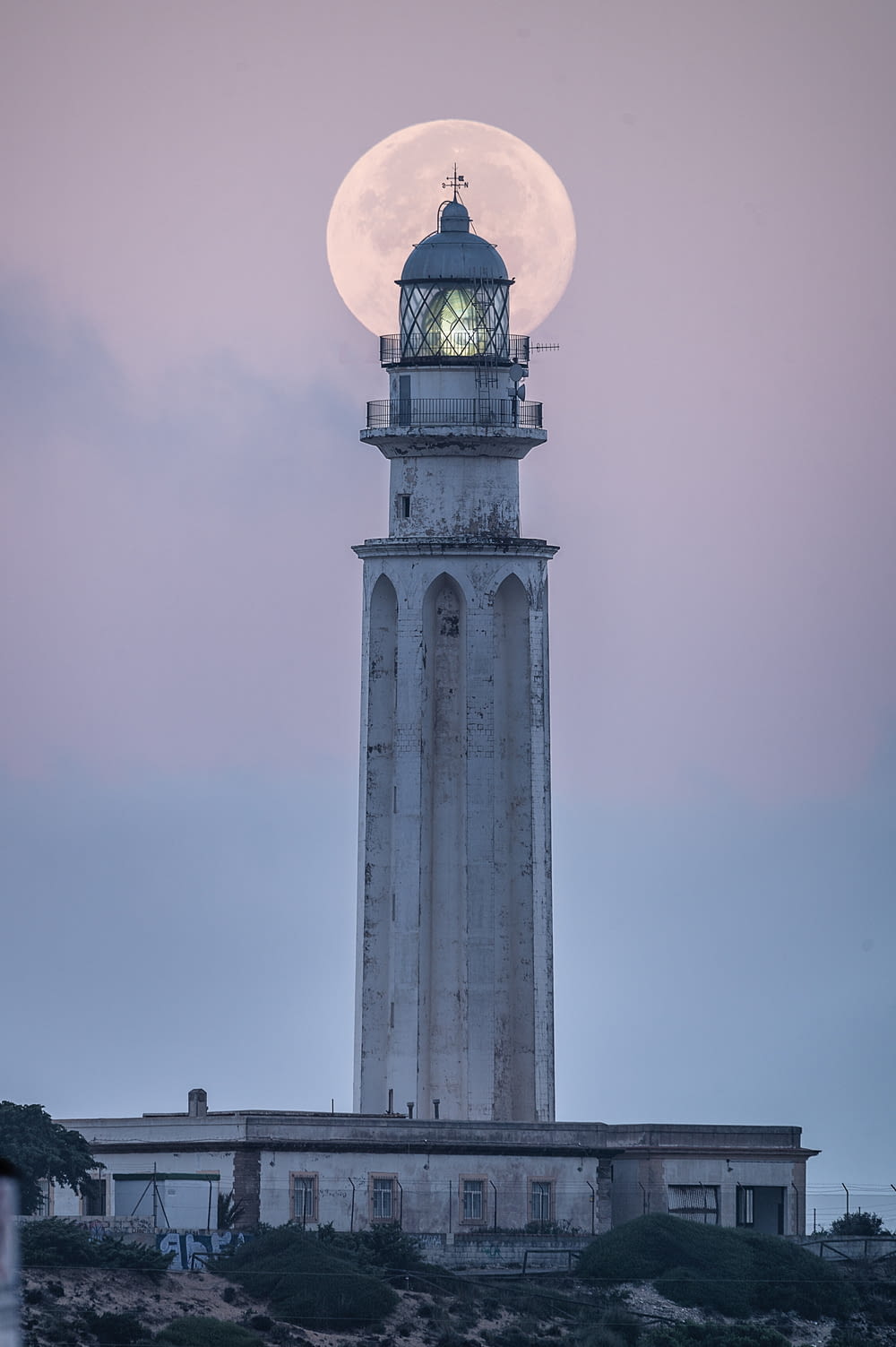 a lighthouse with a full moon in the background