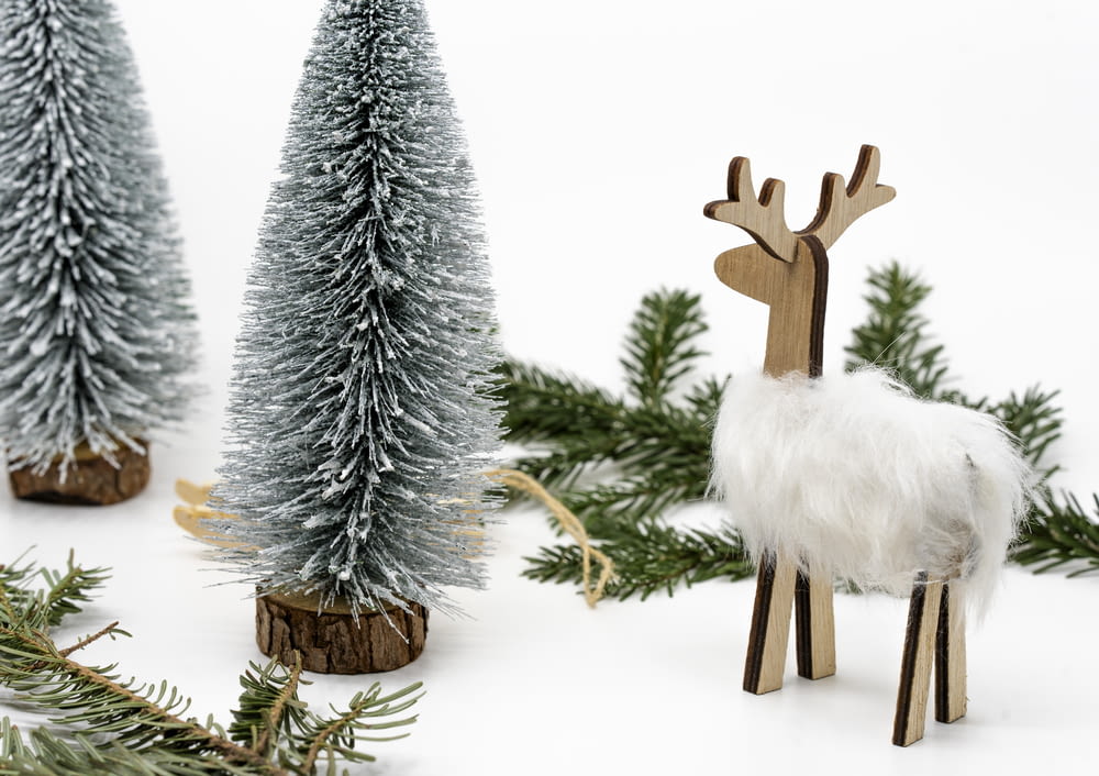 a small wooden reindeer standing next to a christmas tree
