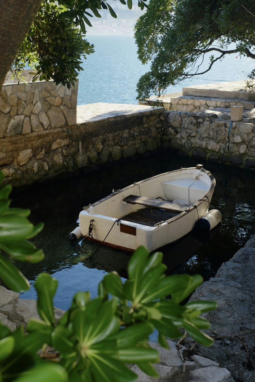 a small boat in the water near a stone wall