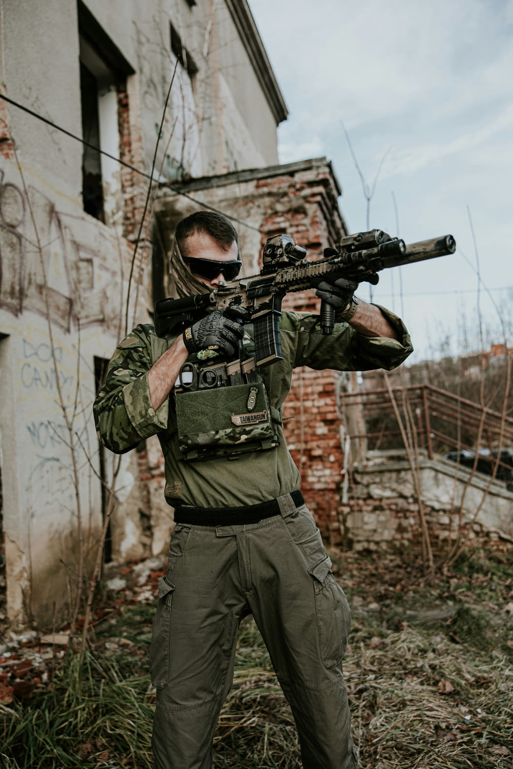 a man holding a rifle in front of a building