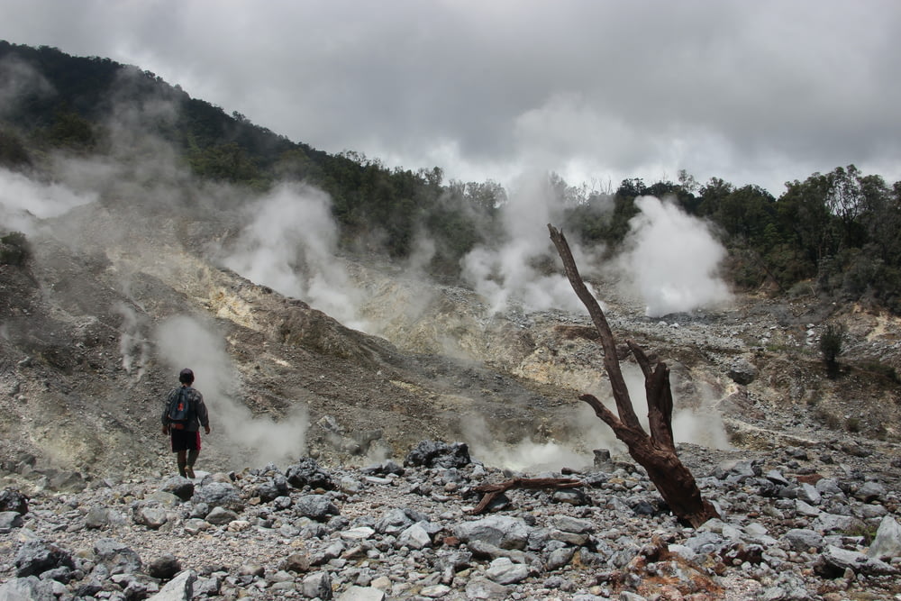 a man standing in a rocky area with steam coming out of the ground