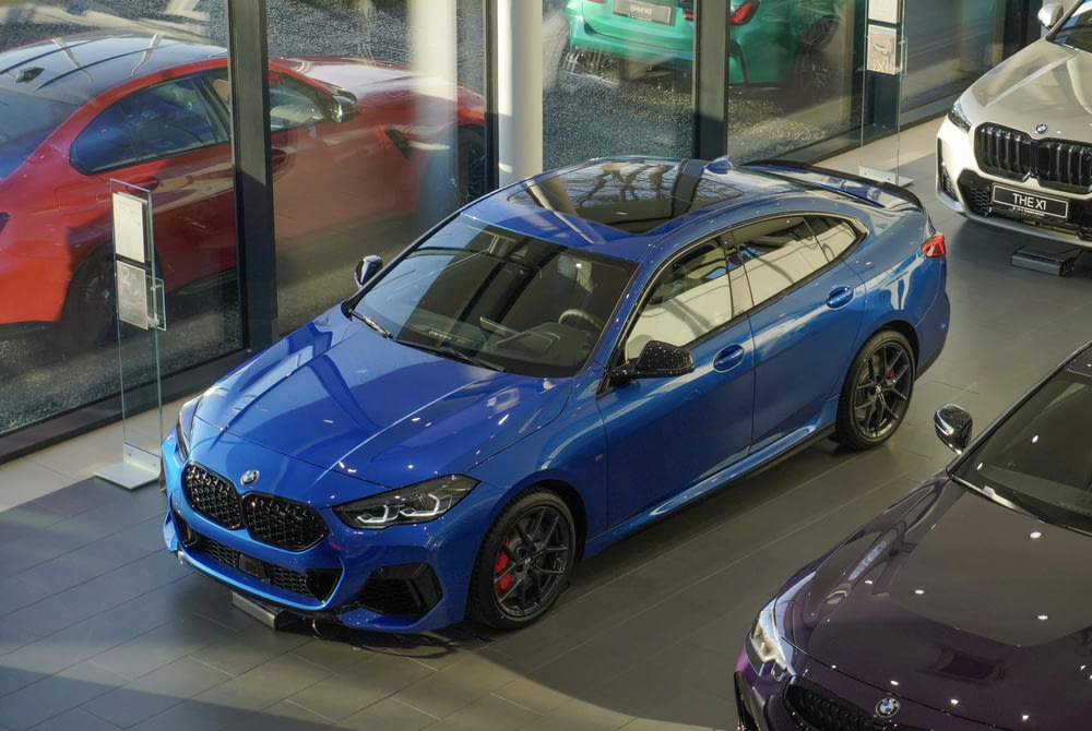 a blue car parked in a showroom next to other cars