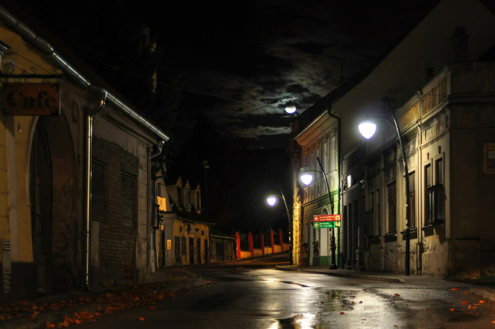 una calle vacía por la noche con una luna llena en el cielo