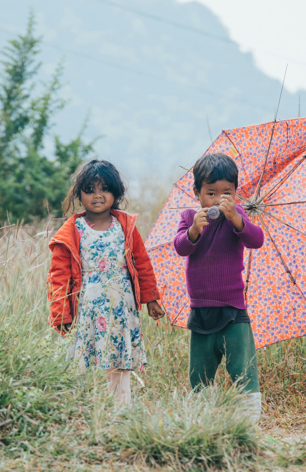 two little girls standing in a field holding umbrellas