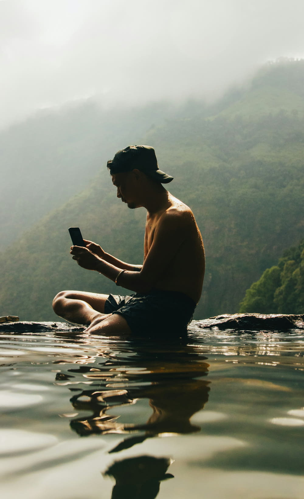 a man sitting in the water looking at his cell phone