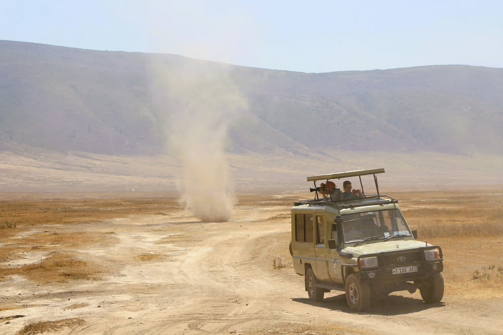 a safari vehicle driving down a dirt road