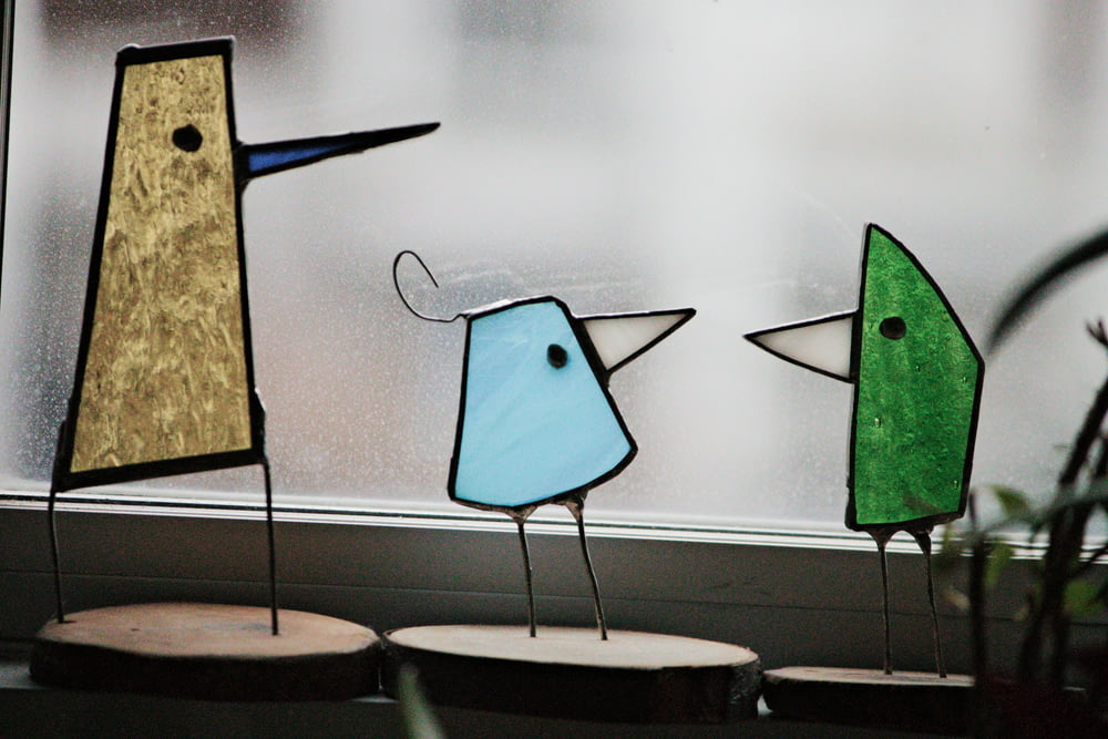 a group of three birds sitting on top of a window sill