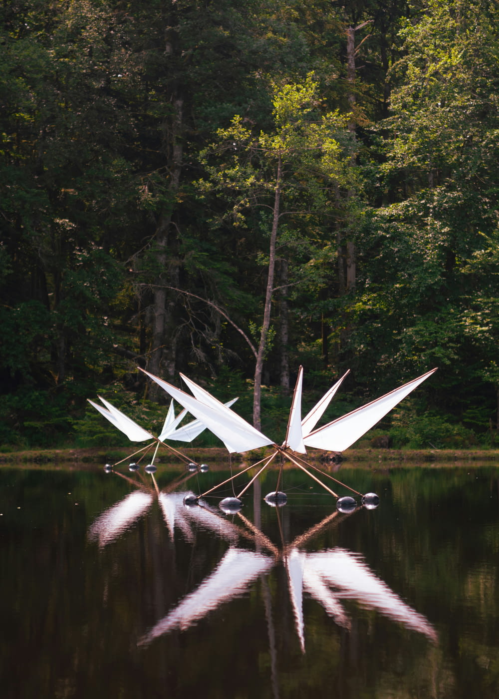 a white sculpture sitting in the middle of a lake