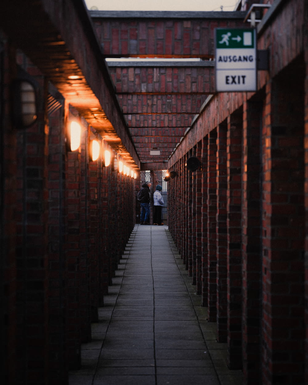 a long brick walkway with a exit sign on it