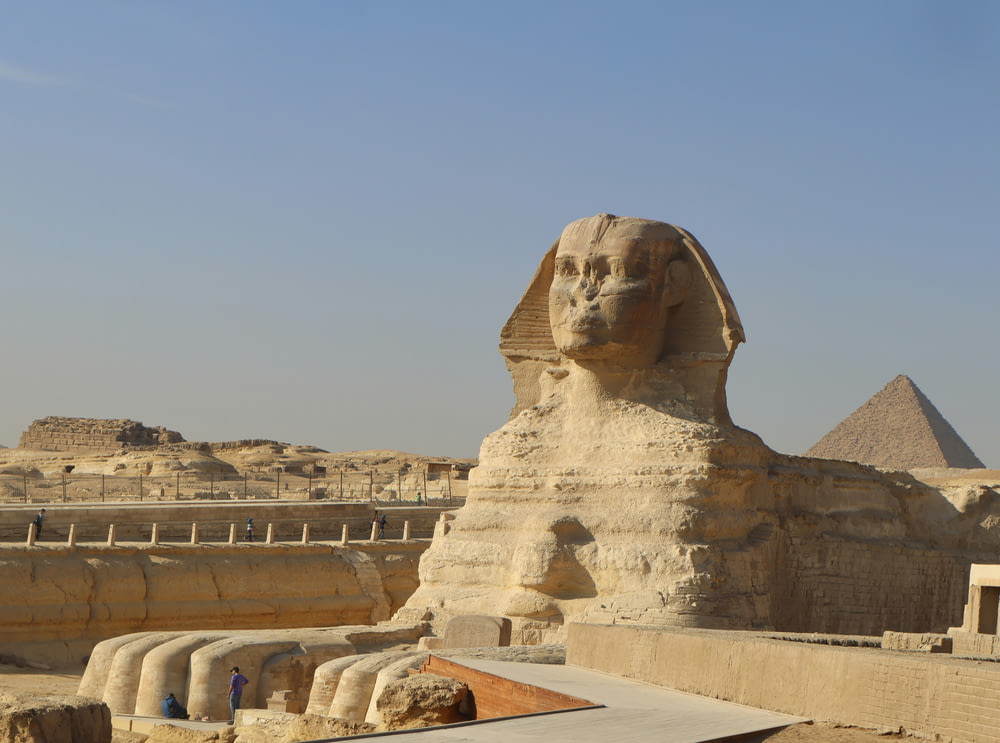a large sphinx statue in front of a pyramid