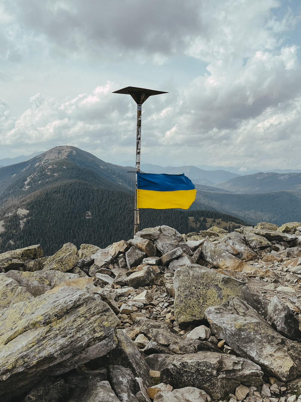 a flag on top of a mountain with a sky background