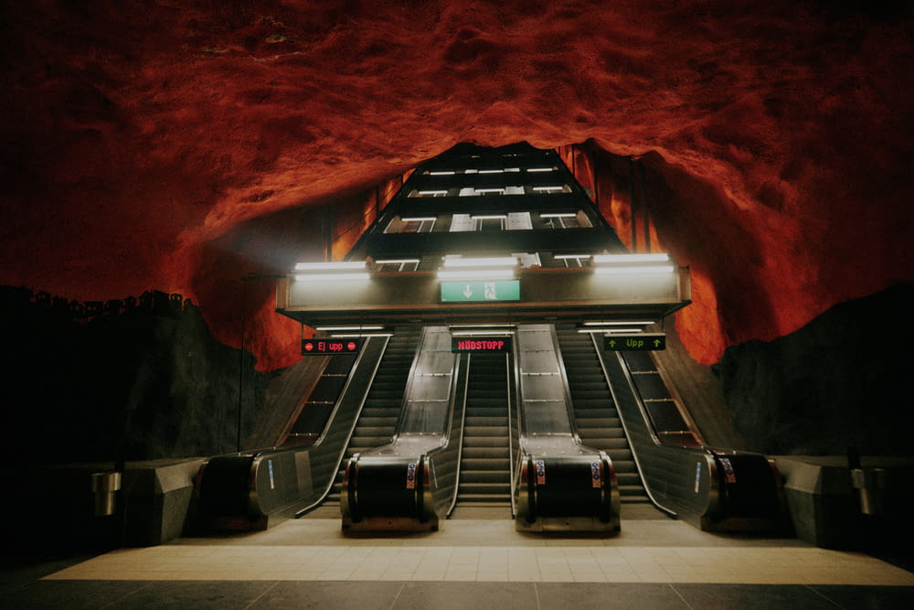 two escalators in a subway station with red walls