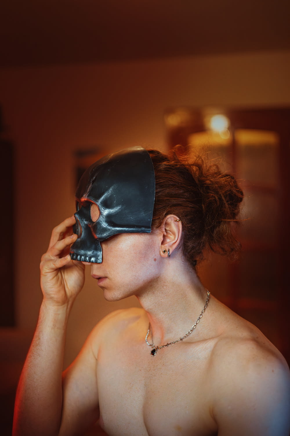 a shirtless woman wearing a leather mask