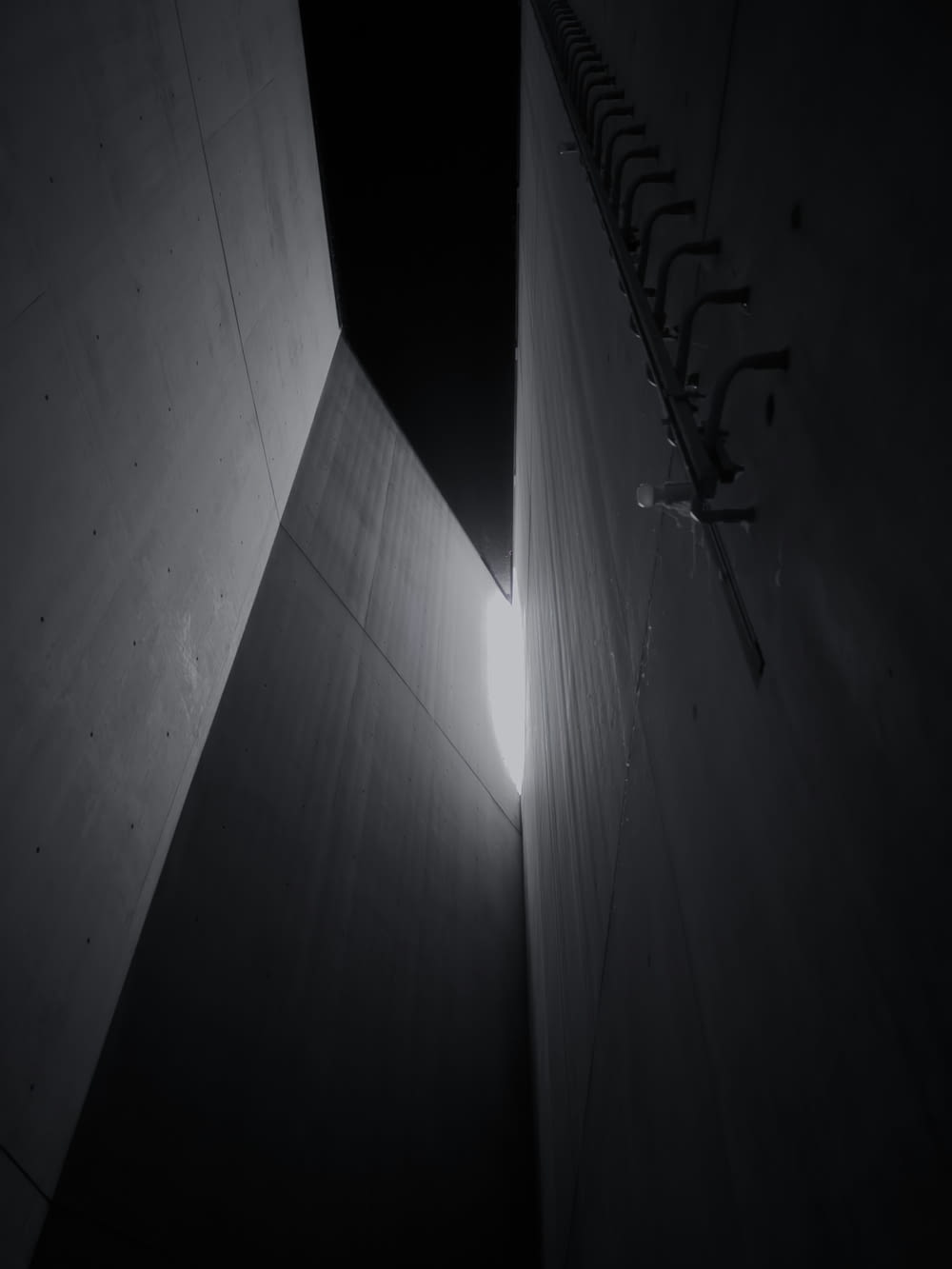 a black and white photo of a light coming through a wall