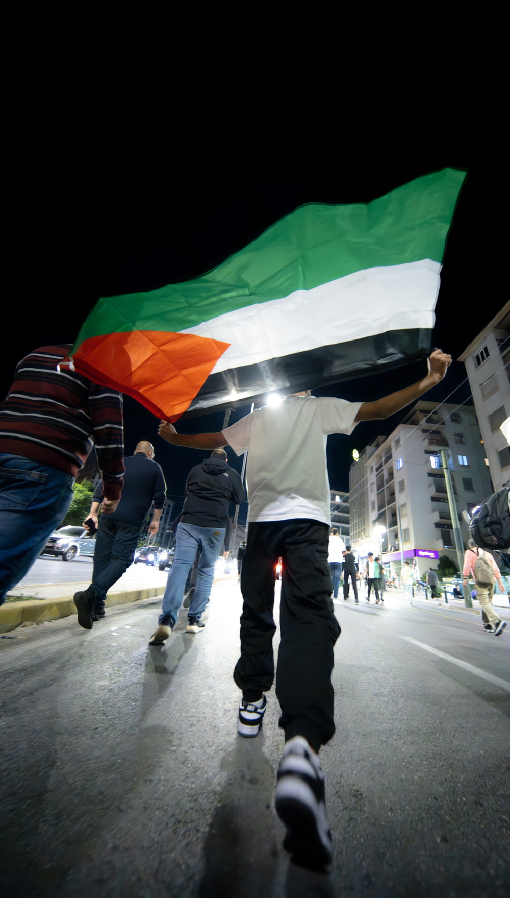 Un grupo de personas caminando por una calle sosteniendo una bandera
