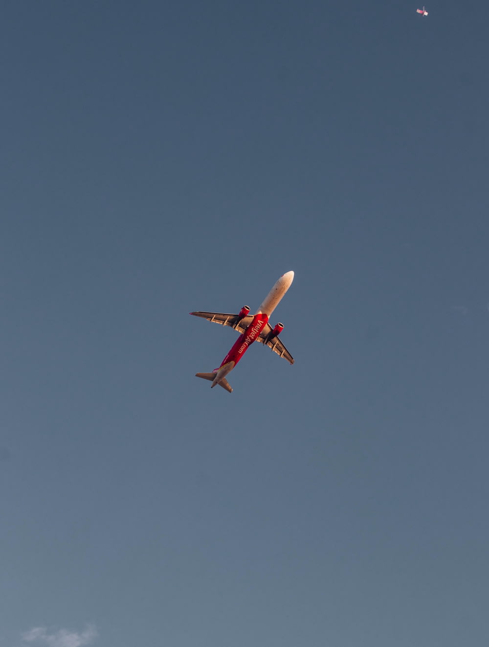 a red and white airplane flying in a blue sky
